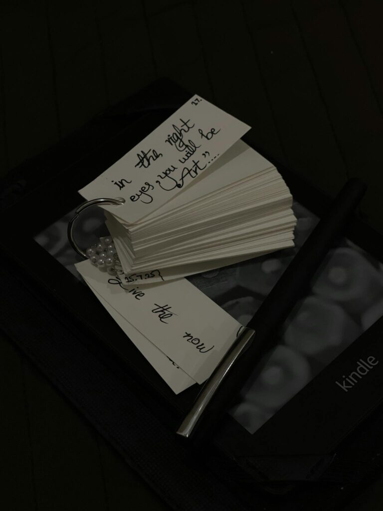 Stack of inspirational quote flashcards, pen, and Kindle for reading inspiration.